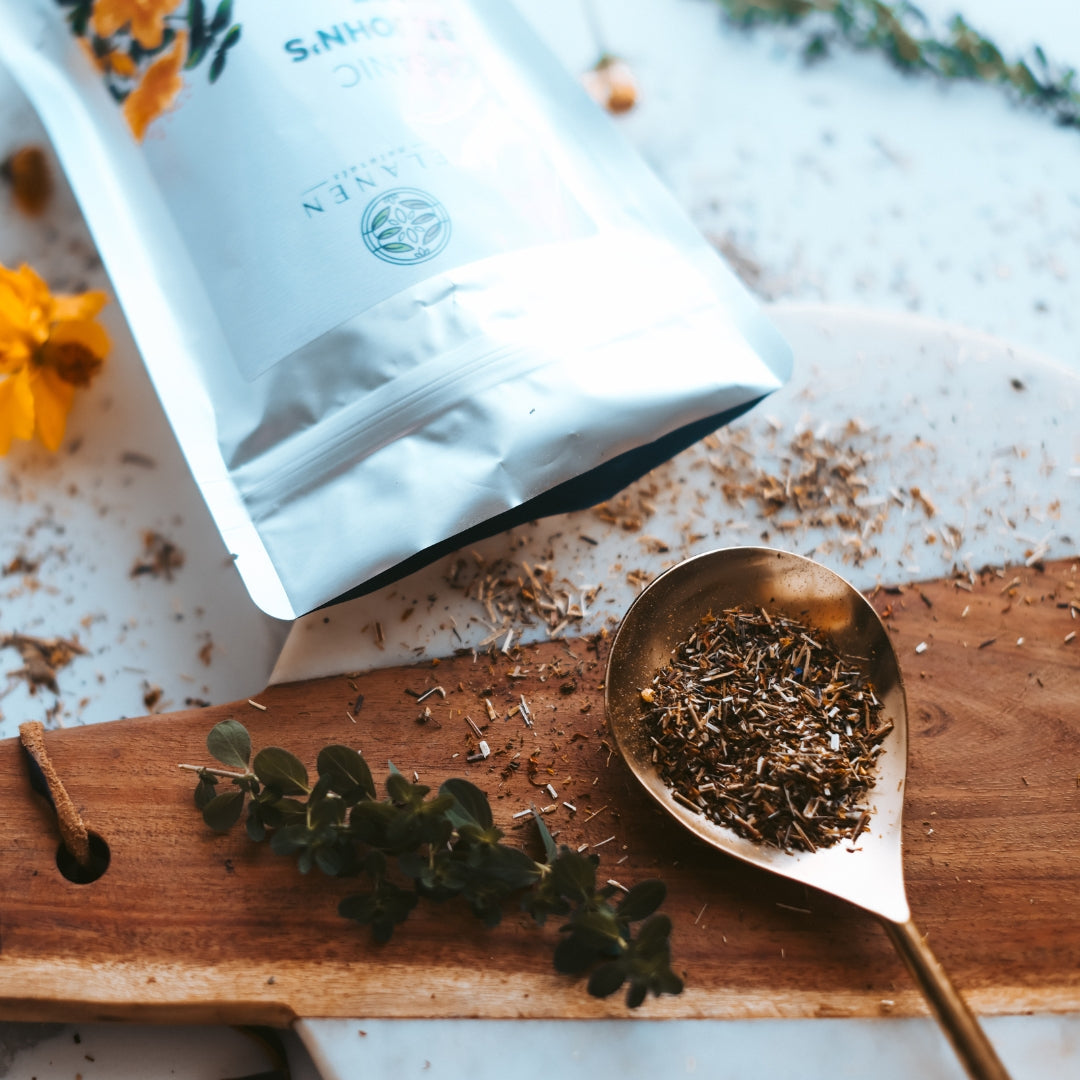 Tea packaging with a spoonful of tea leaves on a wooden board