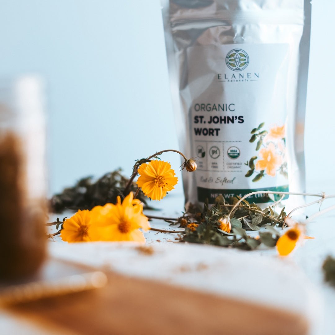 Elanen Organic St. John's Wort packaging with flowers on a blurred background