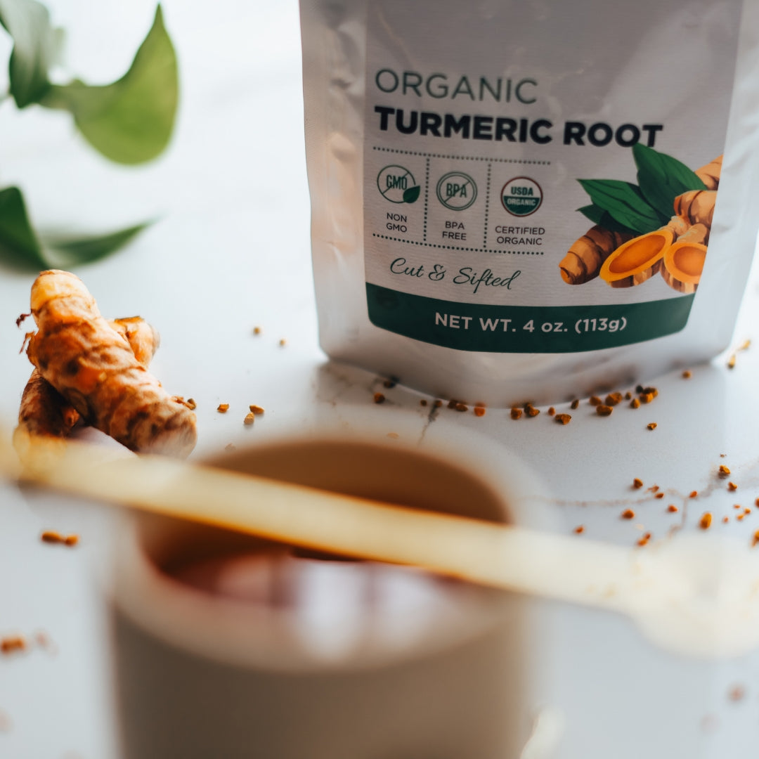 Organic turmeric root packaging with a spoon and turmeric root on a light surface.
