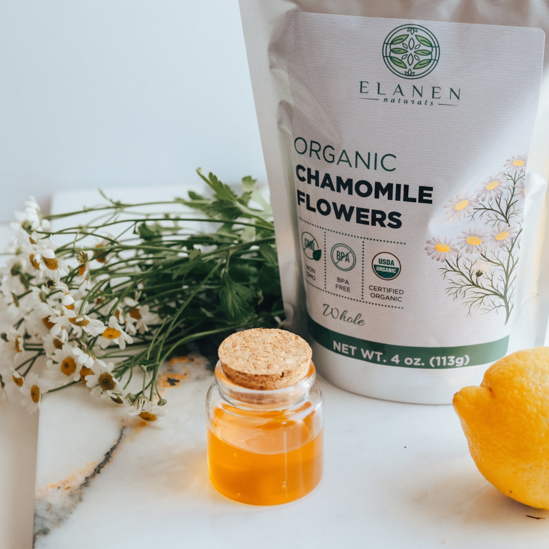 Elanen Organic Chamomile Flowers packaging with a jar of chamomile extract and flowers on a marble surface.