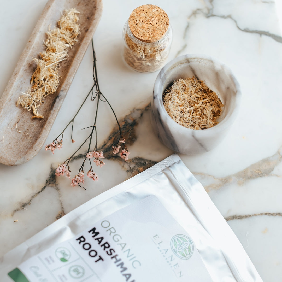 Organic marshmallow root packaging on a marble surface with natural elements.
