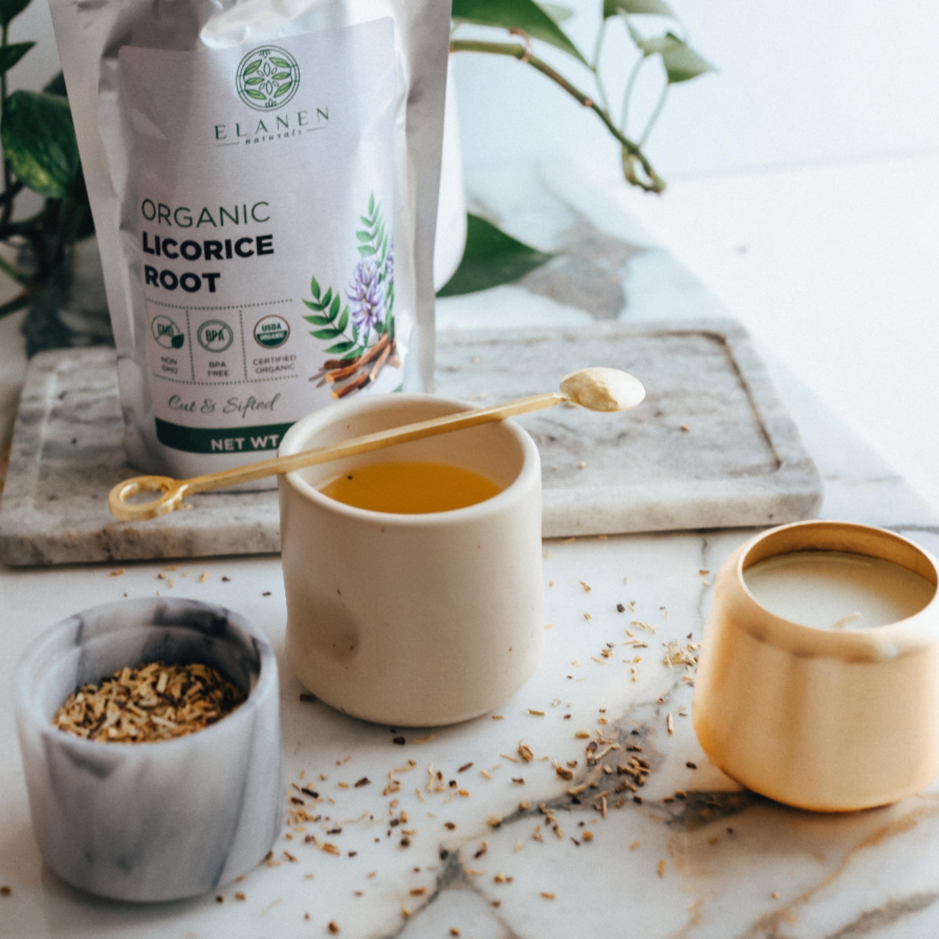 Organic licorice root packaging with a cup of tea and licorice root on a marble surface.