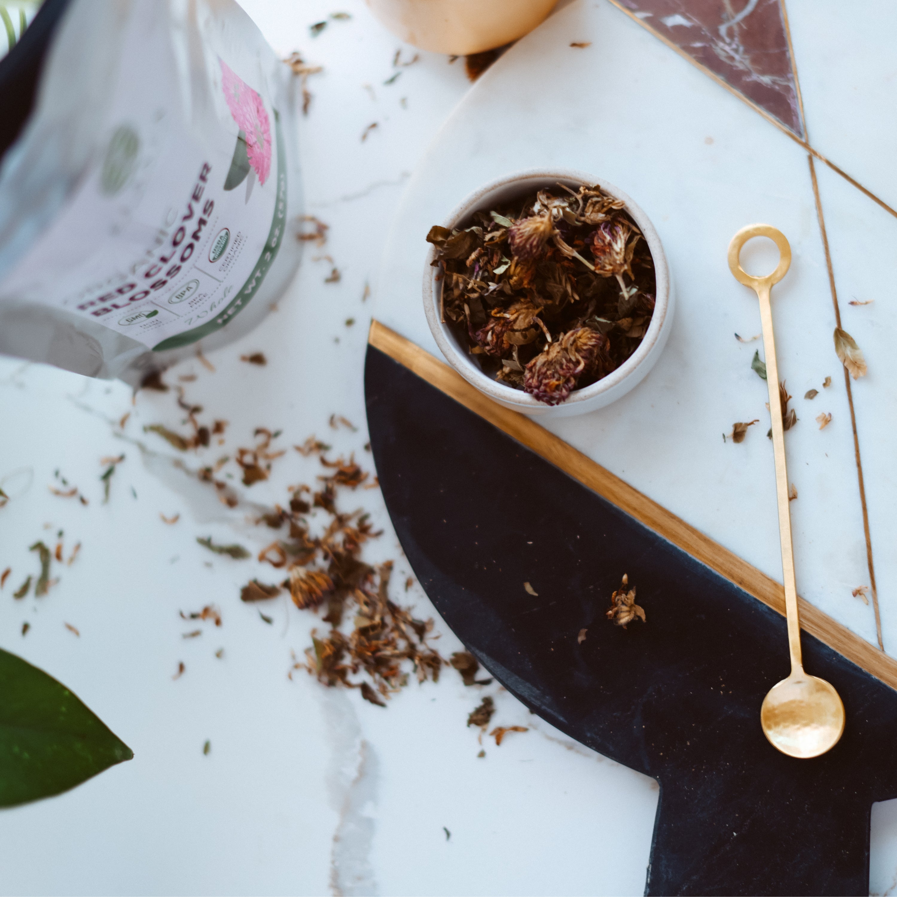 Red clover on a marble surface with a bottle and spoon