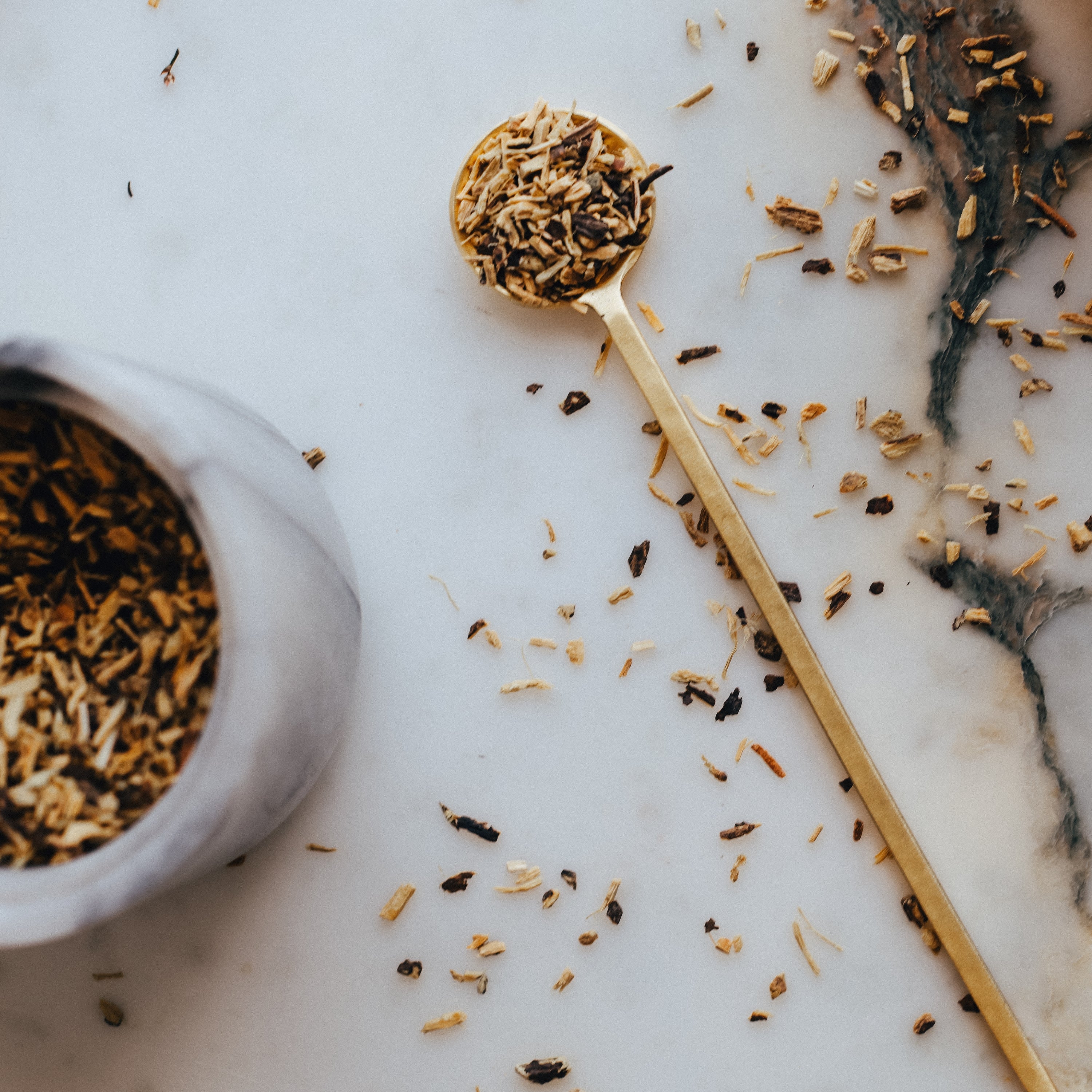 Organic licorice root on a gold spoon and marble surface