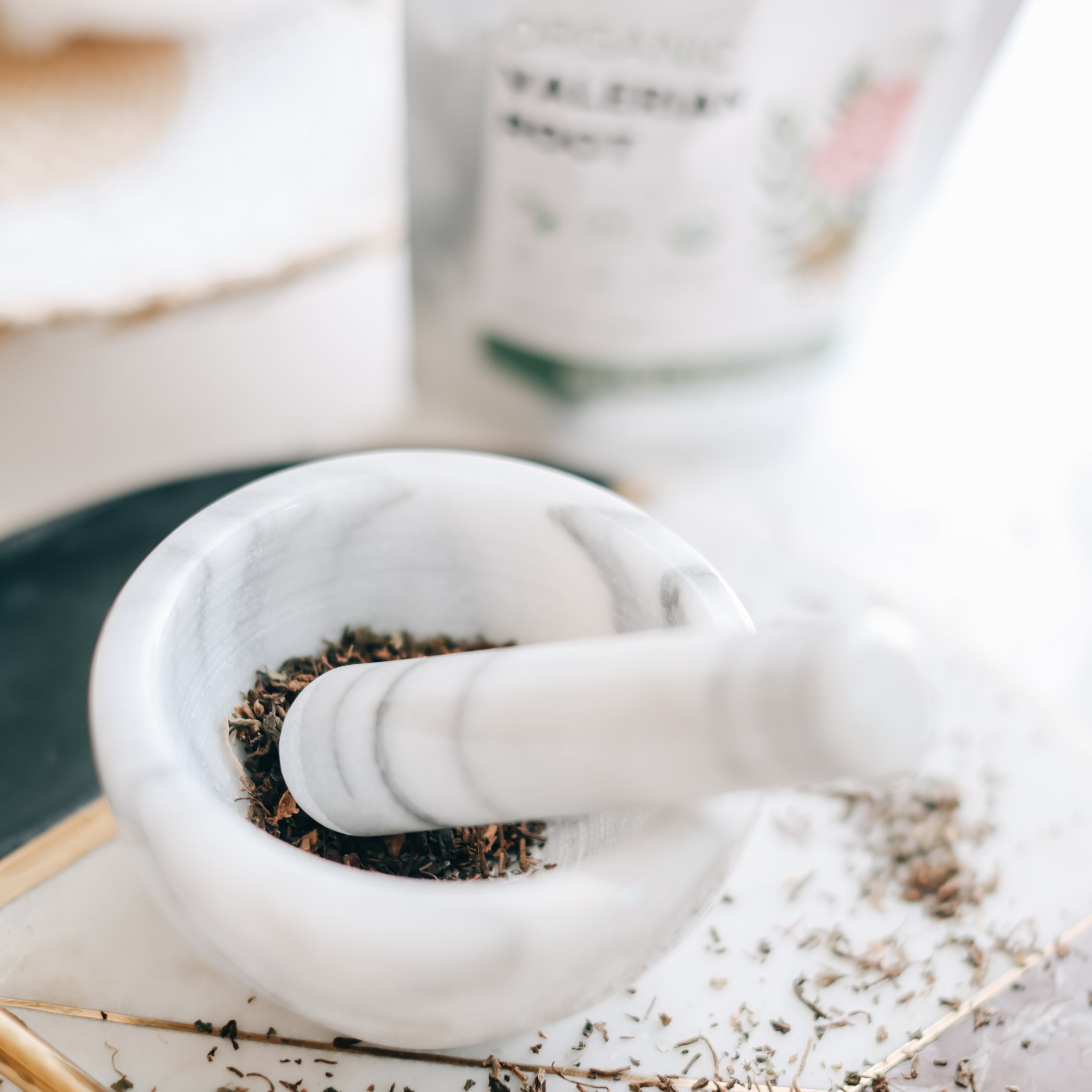 White marble mortar and pestle with dried valerian root on a light surface