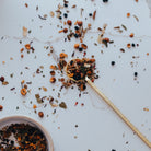 Medicinal herb blend on a white surface with a wooden spoon