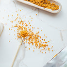 Yellow turmeric root on a white marble surface with a spoon and dish.
