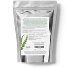 Silver packaging with a white label featuring text and a plant illustration on a white background