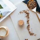 elecampane root on a marble surface with a candle and packaging in the background