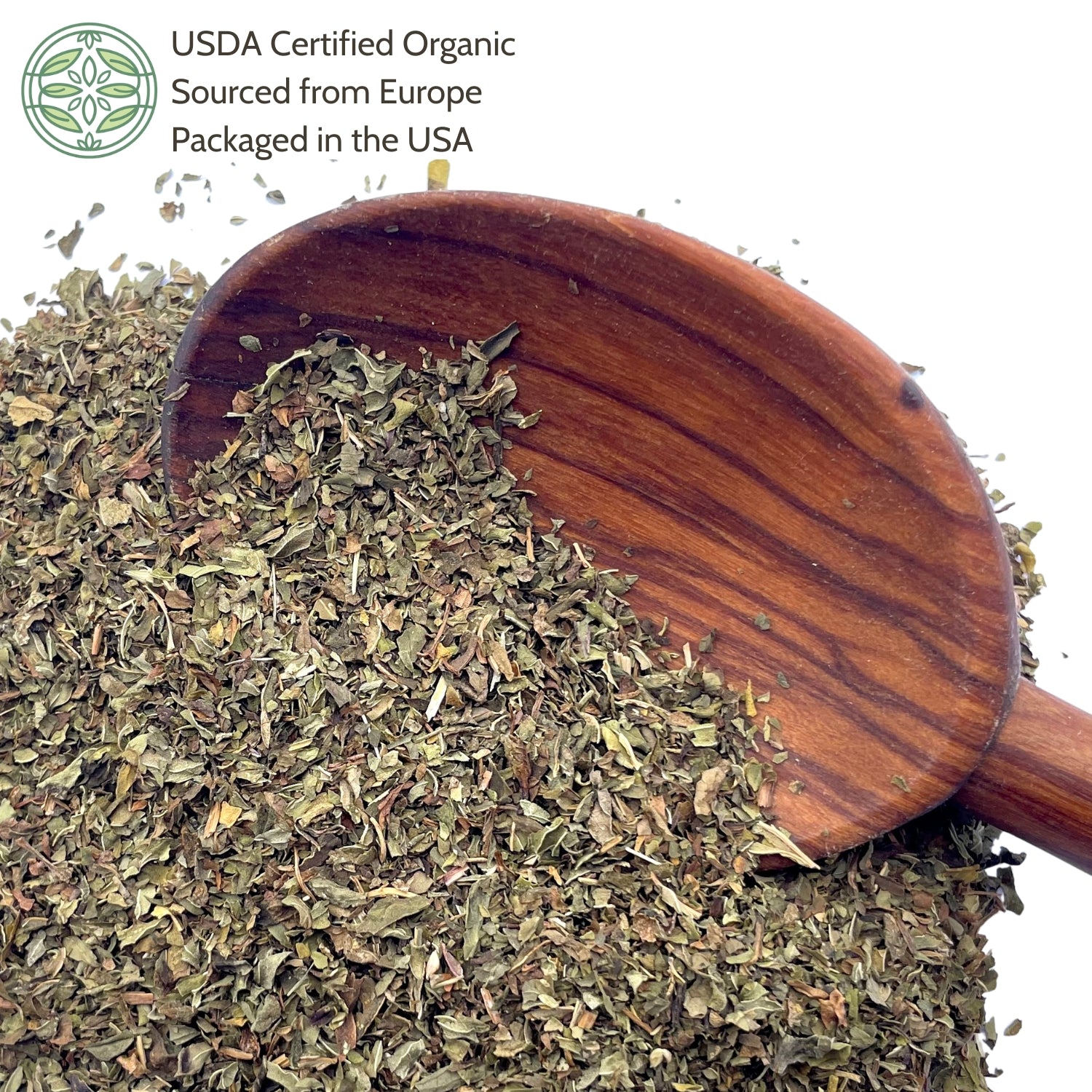 Wooden scoop filled with dried peppermint leaf on a white background.