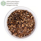 Dried herbs in a white bowl with USDA Certified Organic label on a white background