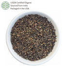 White bowl filled with organic holy basil leaves on a white background, with USDA certification label.