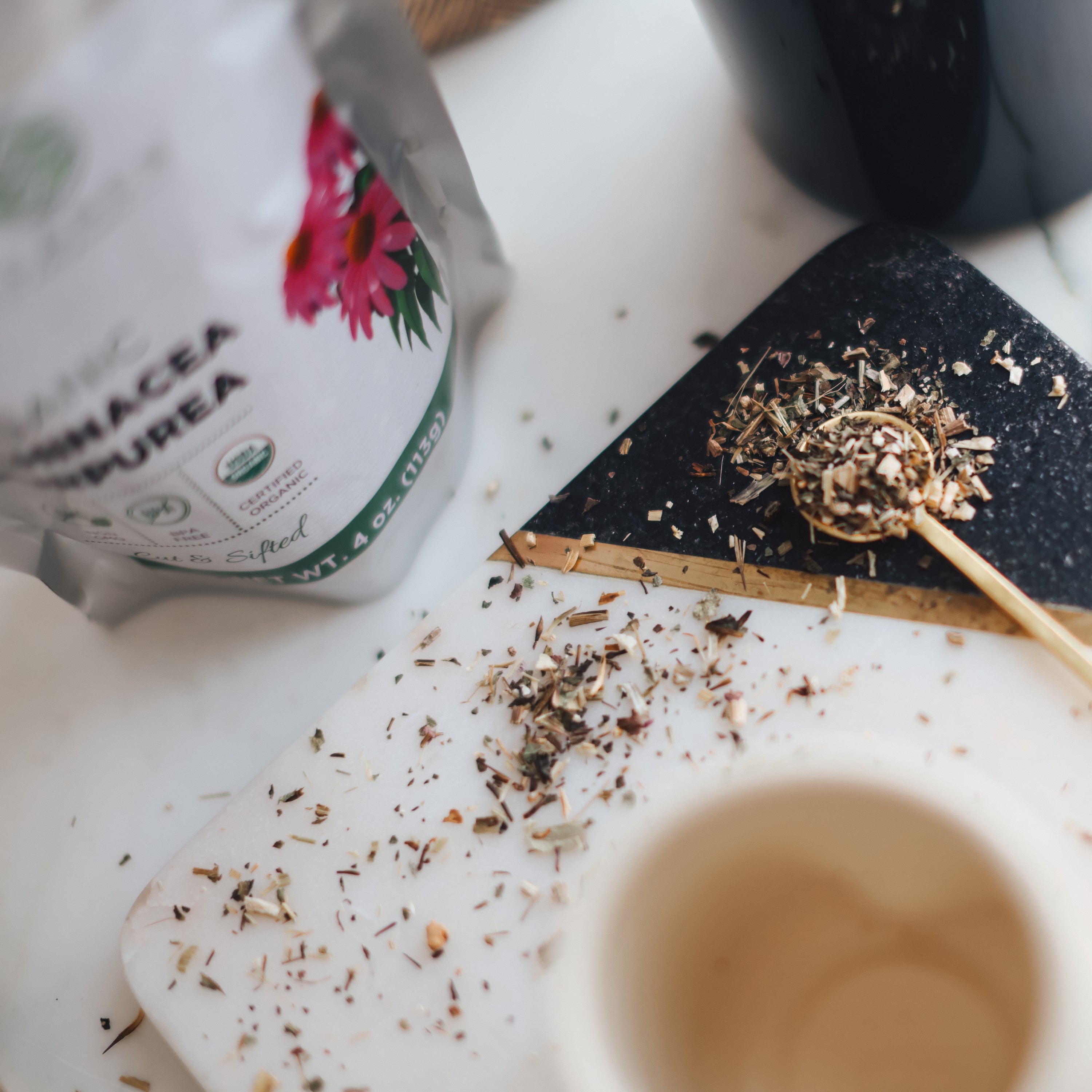 Herbal tea packaging with loose echinacea purpurea leaves on a white surface