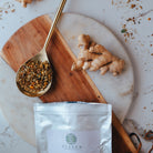 Ginger root, dried herbs, and a package of Elanen on a marble surface.