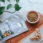 Tea package labeled 'Easy Digest' on a wooden board with a bowl of tea leaves and ginger root.