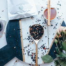 elderberry syrup mix on a wooden spoon with a tea bag and cup of tea on a decorative plate.