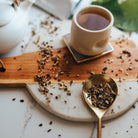 Tea cup with tea leaves on a wooden board and marble surface