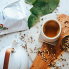 Tea cup with tea leaves and a teapot on a textured surface