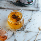 Glass jar of licorice root with a jar of honey on a marble surface