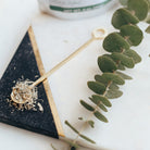 Decorative eucalyptus branch on a white surface with a black triangular object and gold stick.