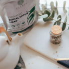 Jar of organic eucalyptus leaf on a marble surface with a candle and notebook.