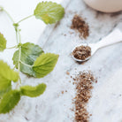 Herbs and a spoonful of dried lemon balm leaf on a marble surface